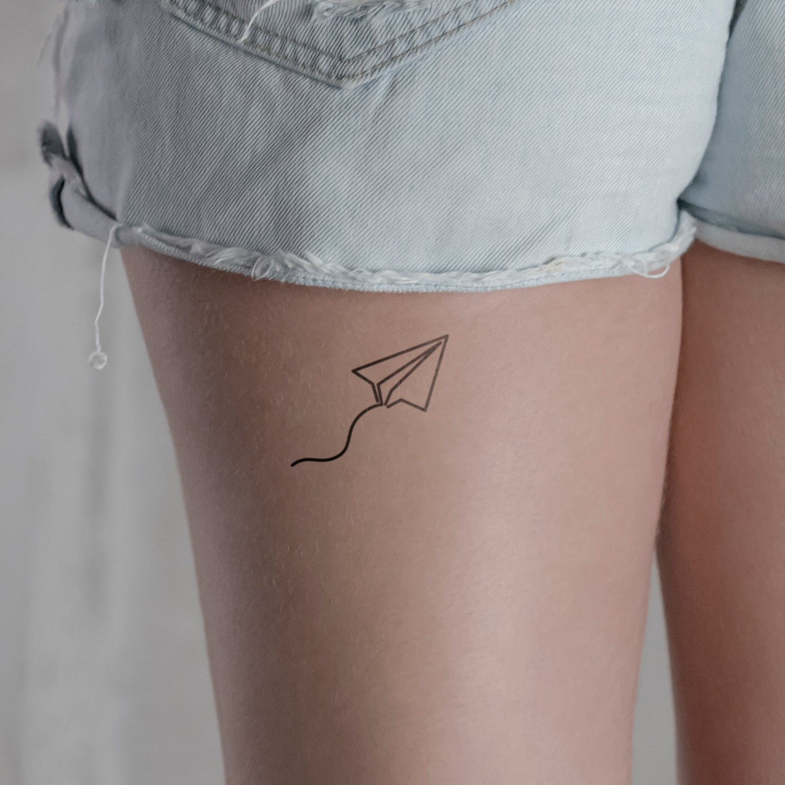 Papierflieger mit Schleife Tattoo von minink, der Marke für temporäre Tattoos.