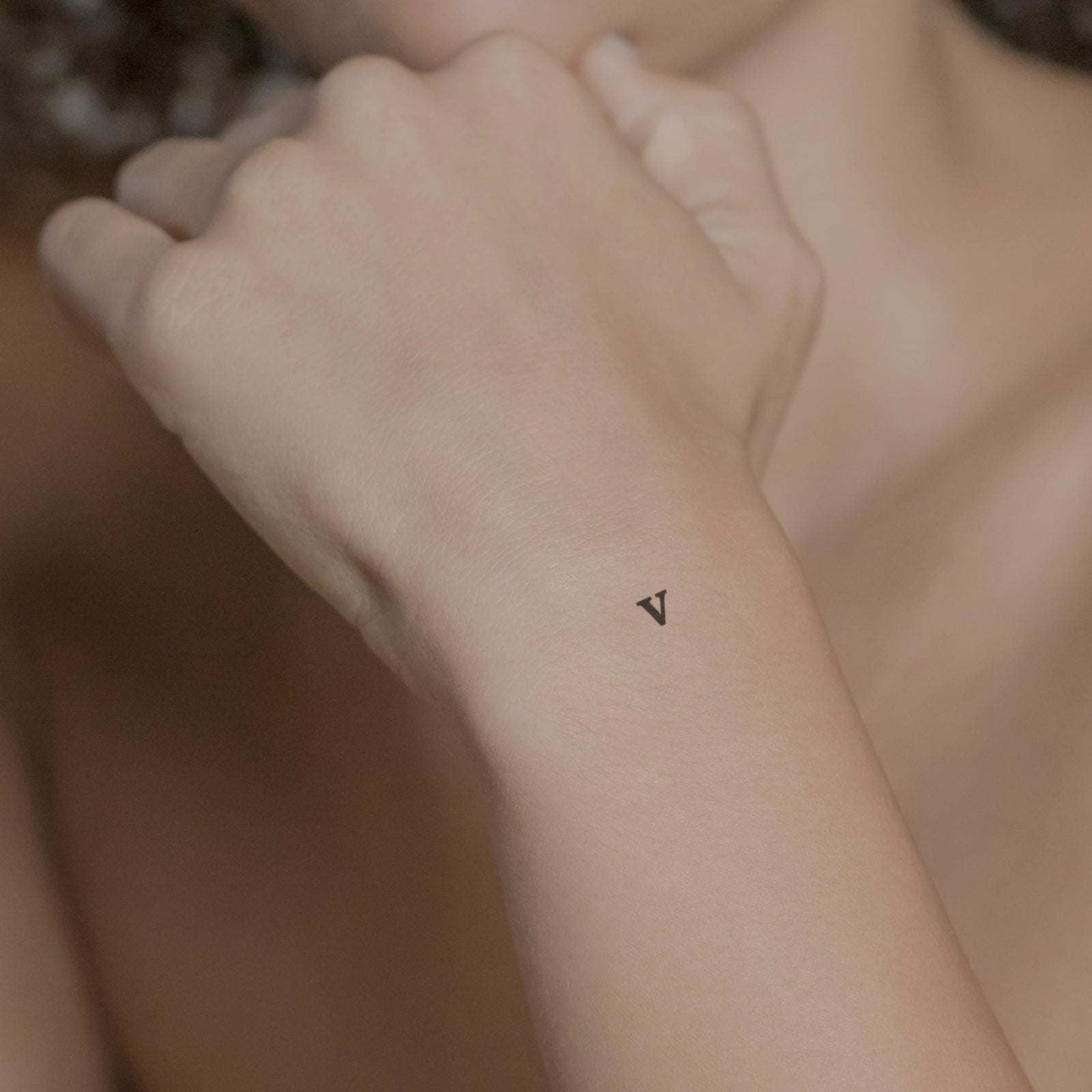 Schriftzug Tattoo Kleinbuchstabe: v von minink, der Marke für temporäre Tattoos.