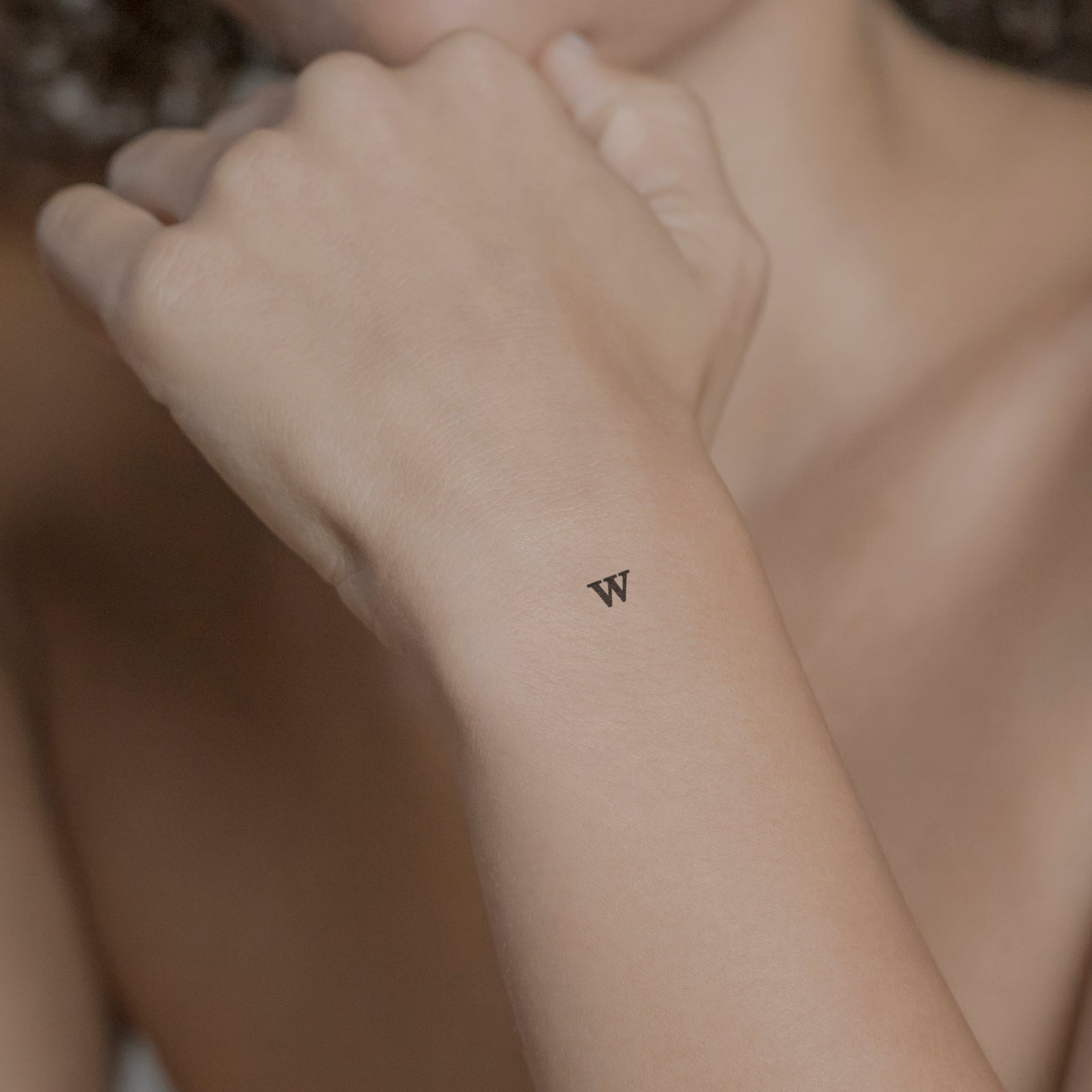 Schriftzug Tattoo Grossbuchstabe: W von minink, der Marke für temporäre Tattoos.