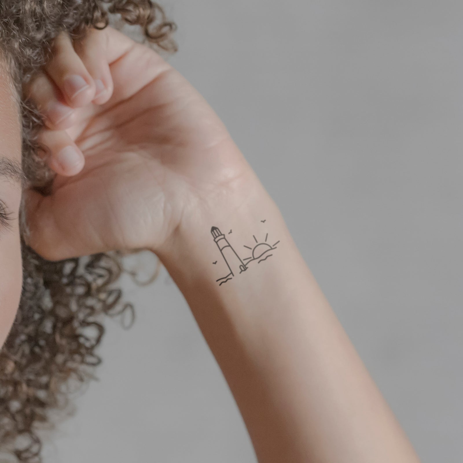 Leuchtturm mit Sonne Tattoo von minink, der Marke für temporäre Tattoos.
